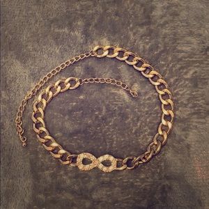 A gold necklaces with silver infinity piece